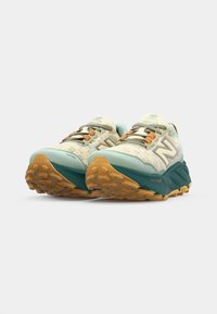 Baskets de course New Balance bleu clair avec une tige en maille, lacets orange et semelle texturée verte. Les caractéristiques comprennent une semelle intermédiaire rembourrée et des accents de logo.