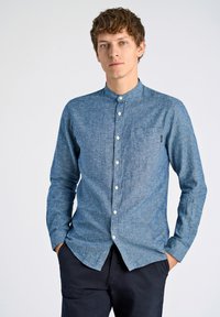 Camicia azzurra in chambray a maniche lunghe con colletto alla francese, taschino frontale e bottoni bianchi, caratterizzata da un tessuto testurizzato.