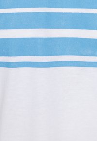 T-shirt à rayures avec des lignes horizontales épaisses bleues et blanches alternées sur un tissu doux, montrant une texture lisse.