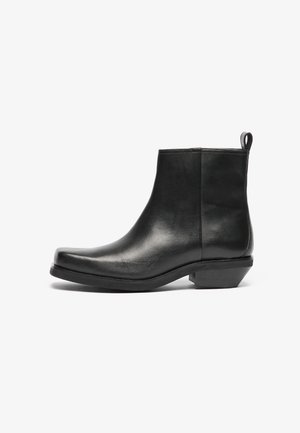 Botas negras de cuero hasta el tobillo con punta afilada y tacón bajo. Diseño elegante con una textura suave y una cinta de tirón para facilitar su uso.