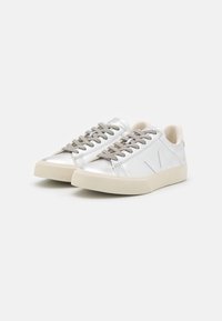 Silver leather sneakers with beige rubber sole, round toe, and gray laces. Features a logo on the side and smooth texture.
