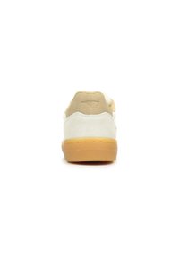 Beige en witte suède sneaker met een gumrubberen zool, weergegeven vanuit de achterkant, met een gestikt logo op de hieltab.