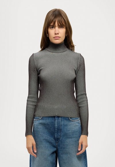 Pull à col roulé ajusté en tissu gris métallisé côtelé, manches longues, avec une texture lisse. Associé à un pantalon en denim bleu ample.
