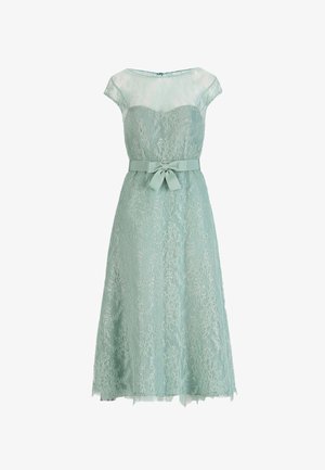 Svetlo zelena čipkasta midi obleka s prosojnimi kratkimi rokavi, izrezom v obliki srca in pentljo, vezano v pasu.