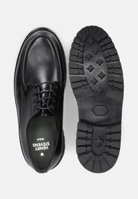 Zwarte leren schoenen met een ronde neus, vetersluiting en een dikke, gestructureerde rubberen loopzool met antislipprofielen.
