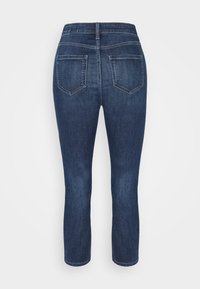 Jeans de mezclilla azul oscuro con un diseño ajustado, cintura alta y bolsillos traseros. La tela presenta una textura suave y un ligero desgastado.