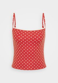 Red polka dot tank top with thin straps, ribbed texture, and a fitted shape. Features white dots on the fabric, with a scalloped edge.