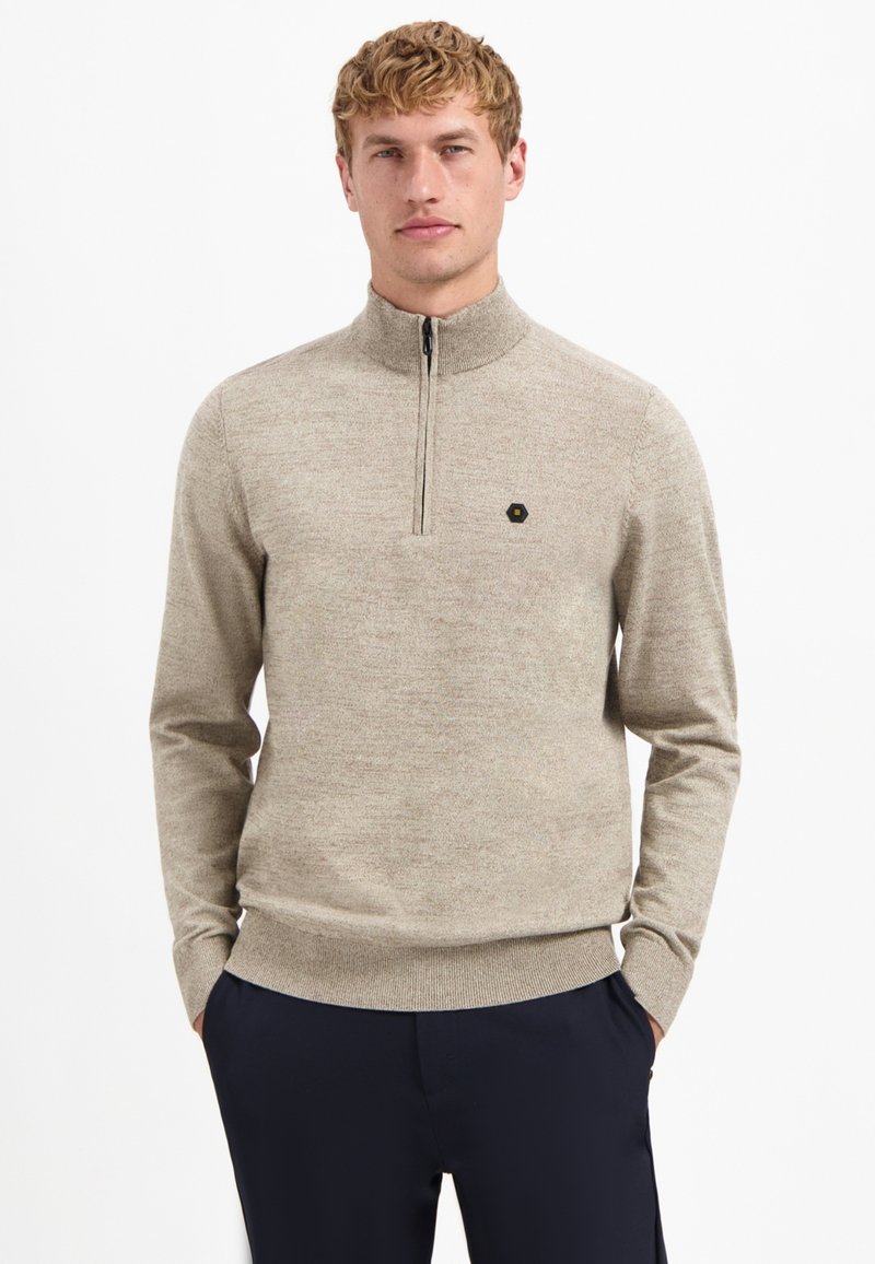 Beige gestrickter Pullover mit einem mit Reißverschluss versehenen hohen Kragen, Rippbündchen und Saum. Mit einem kleinen schwarzen Sechseck-Logo auf der Brust.