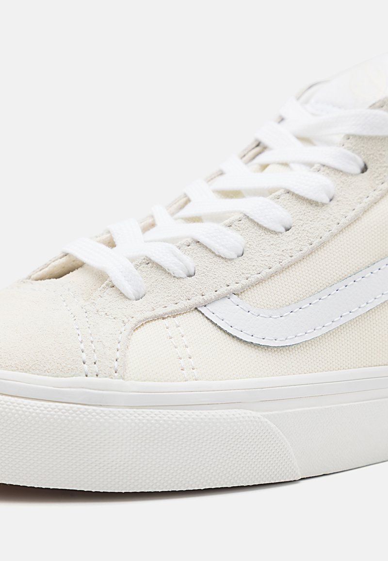 Baskets en toile avec un dessus crème texturé, des accents en daim blanc, des lacets blancs et une semelle en caoutchouc avec un motif de semelle texturé.