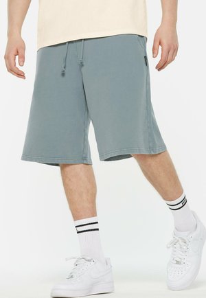 Light gray cotton shorts with an elastic waistband and drawstring. Paired with white sneakers and striped white socks.