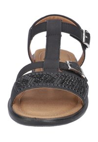 Sandalo nero con una larga fascia decorata con perforazioni. Fibbia regolabile, soletta ammortizzata e suola piatta.