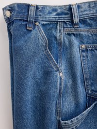 Blå denimjeans i medium blå med en falmet finish. Funksjoner inkluderer knappelukking, fem lommer og oransje søm detaljer.