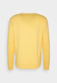 Sudadera amarilla de tejido suave de mezcla de algodón, con mangas largas, cuello redondo y un diseño de espalda simple y sin costuras.