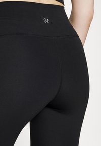 Musta korkeavyötäröinen legginsit pehmeästä, joustavasta kankaasta. Ominaisuuksiin kuuluu hienovarainen valkoinen logo vyötäröllä ja litteät saumat mukavuutta varten.