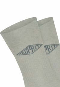 Graue gestrickte Socken mit gerippter Textur, die auf der Seite ein blaues Logo in Diamantform aufweisen. Nahaufnahme des Bündchens und des Musters.