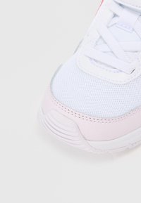 Baltie sporta apavi ar režģa virsu un rozā ādas akcentiem. Apaļš purngals, teksturēta virsma un plakanas šņores. Viegls dizains.