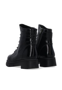 Schwarze Lederkampfstiefel mit glänzender Oberfläche, Schnürung vorne und seitlichem Reißverschluss. Chunky Gummisohle mit strukturierten Details.