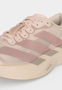 Ροζ ανοιχτό αθλητικό παπούτσι Adidas με τρεις πιο σκούρες ροζ ρίγες, πλεκτό επάνω μέρος, ελαφριά μαλακή σόλα με την ένδειξη "Lightstrike Pro" και ταιριαστά κορδόνια.