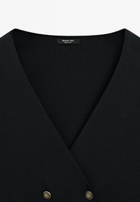 Schwarzes, geripptes Strickkleid mit V-Ausschnitt, vorne mit doppelten Messingknöpfen und glatter Textur. Etikett innen sichtbar.