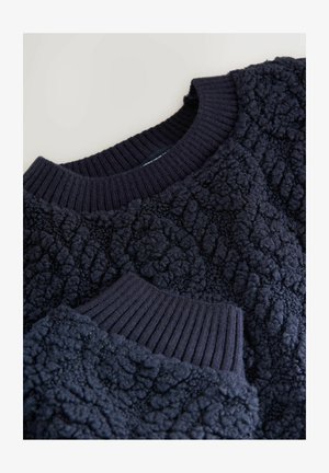 Navy blue textured fleece sweater with ribbed neckline and cuffs shown in close-up on a light background.