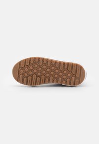 Semelle de chaussure en matériau caoutchouteux, présentant un motif hexagonal et des rainures texturées de couleur brun clair, conçue pour l'adhérence.