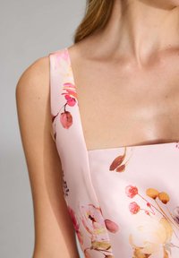 Blumenmusterkleid aus weichem pinkfarbenem Stoff; mit breiten Trägern, quadratischem Ausschnitt und lebendigen Aquarellblumen in Orange- und Rosatönen.