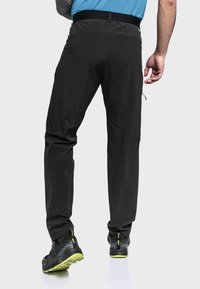 Schwarze, leichte, dehnbare Hosen mit strukturierter Oberfläche und elastischem Bund. Mit schmal zulaufenden Beinen und seitlichen Reißverschlusstaschen.