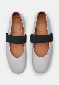 Ballerine in pelle bianca con una fascia elastica nera sul collo del piede, dotate di una morbida soletta in pelle color tan e dettagli di cucitura minimi.