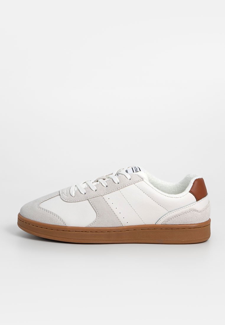 Weiße Leder-Sneaker mit tanfarbener Gummisohle, strukturierten Wildleder-Akzenten und durchbrochener Detailgestaltung. Schnürsenkel und ein kleines Logo auf der Zunge.