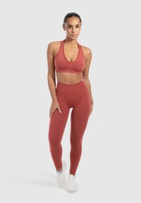 Rode sportoutfit bestaande uit een crop top met een diepe V-hals en hoge taille leggings. Glad, rekbaar materiaal met minimale naden.