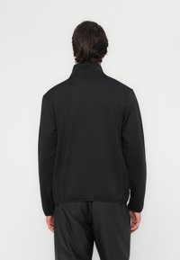 Black zip-up jacket with a high collar and long sleeves. Smooth texture, minimalistic design, and a relaxed fit. Seams visible at edges.