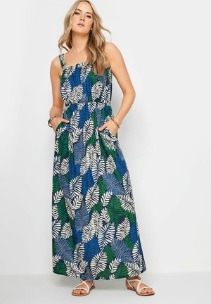 Robe maxi avec un motif de feuilles bleues, vertes et blanches. Dotée de bretelles, d'un corsage ajusté et de poches sur les côtés. Fabriquée en tissu léger.