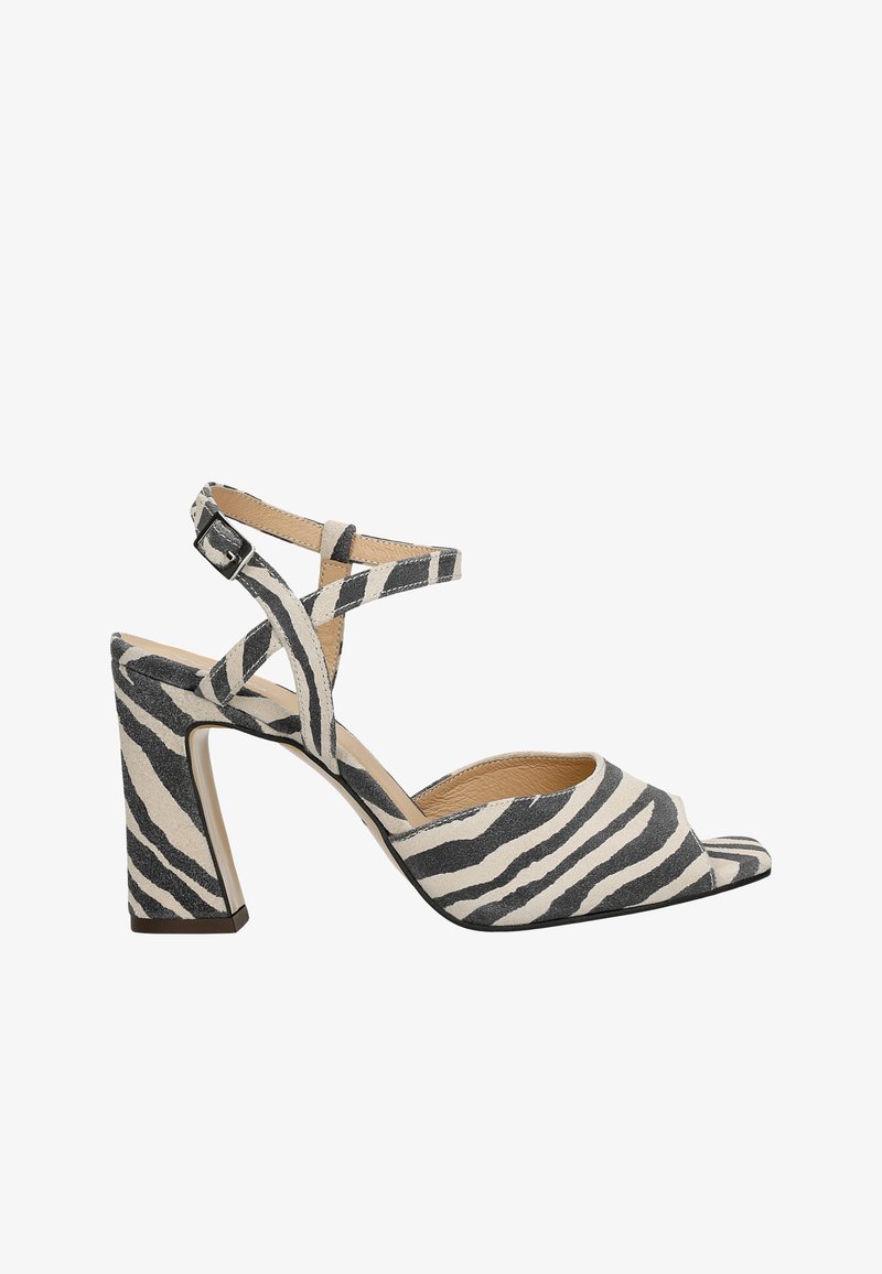 Sandales à talons ouvertes en tissu à motifs zèbre, avec des sangles croisées autour de la cheville et un talon épais solide. Couleur : noir et crème.
