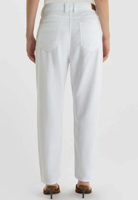 Witte denim broek met een rechte pijp, voorzien van achterzakken en een lichte textuur, gedragen met bruine sandalen met hak.