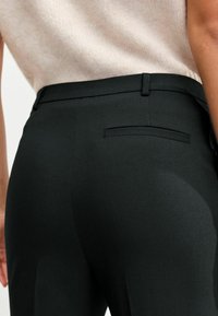 Černé tailorované kalhoty, hladká tkanina, přiléhavý design, středně vysoký pas, obsahující zadní kapsu s elegantním zpracováním a minimálním švem.