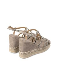 Sandali con zeppa beige caratterizzati da una texture simile al camoscio, cinturini incrociati e borchie metalliche, con una suola in corda intrecciata di juta.