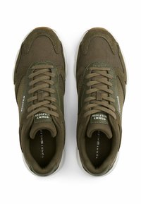 Zapatillas marrones y verde olivo con parte superior de malla, acentos de ante y suela de goma blanca. Cuenta con cordones redondos y etiquetas con el logo en la lengüeta.