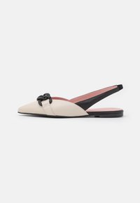 Beige bőr slingback lapossarkú cipők, hegyes orral, fekete akcentussal és dekoratív pánttal az elején. Az talp lapos és sima.