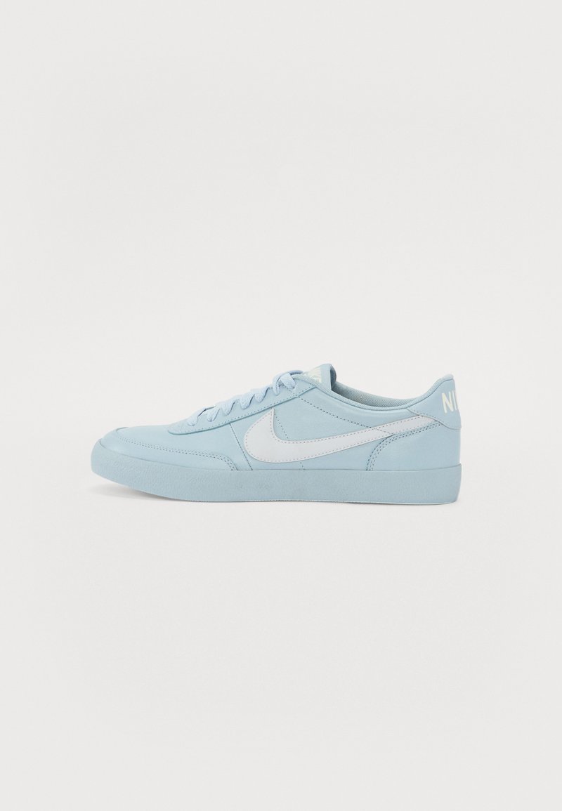 Baskets Nike bleu clair avec un dessus en daim lisse, swoosh blanc, lacets plats et semelle en caoutchouc texturée. Design minimaliste avec un détail de marque.