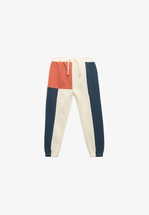 Cotton blend jogger pants featuring a color-blocked design in cream, navy, and rust with an elastic waistband and ankle cuffs.