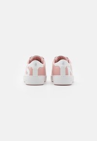 Rosa lädersneakers med vita accenter, rund tå, platt vit sula och en logodetalj på baksidan av hälen. Slät textur, enkel design.