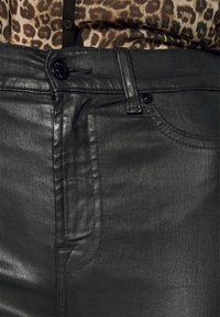 Jeans de denim negro con recubrimiento que presentan una textura suave, diseño de cinco bolsillos y ajuste slim. Incluyen un cierre de botón y cremallera.