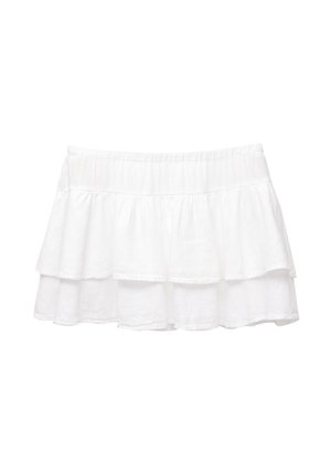 Witte gelaagde rok gemaakt van lichte stof. Voorzien van een elastische tailleband en drie gelaagde volants, wat een vloeiende silhouet creëert.