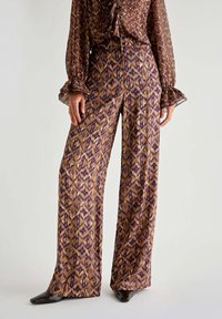 Weite Hosen aus einem seidigen Stoff mit einem braun-lila geometrischen Muster. Hoch tailliertes Design mit glatter Oberfläche und dezentem Glanz.