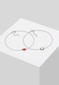 Silver kedjeset med ett charm i röd och svart nyckelpiga samt ett charm i guldton av en hälg. Fin snoddade länkar och justerbart lås.