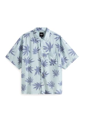 Chemise à manches courtes en tissu bleu clair, arborant un motif de feuilles violettes et une poche poitrine. Logo de la marque visible sur la manche.