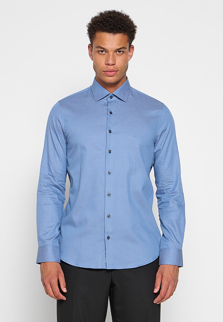 Chemise à manches longues, bleu clair, avec un motif texturé et des boutons foncés. Caractéristiques : col classique et coupe ajustée.