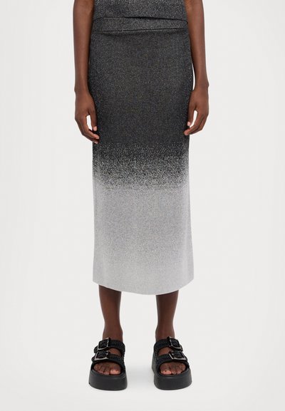 Fustă până la genunchi cu un gradient de la negru la alb. Fabricată dintr-un material tricotat metalic cu textură. Asortată cu sandale negre cu catarame.