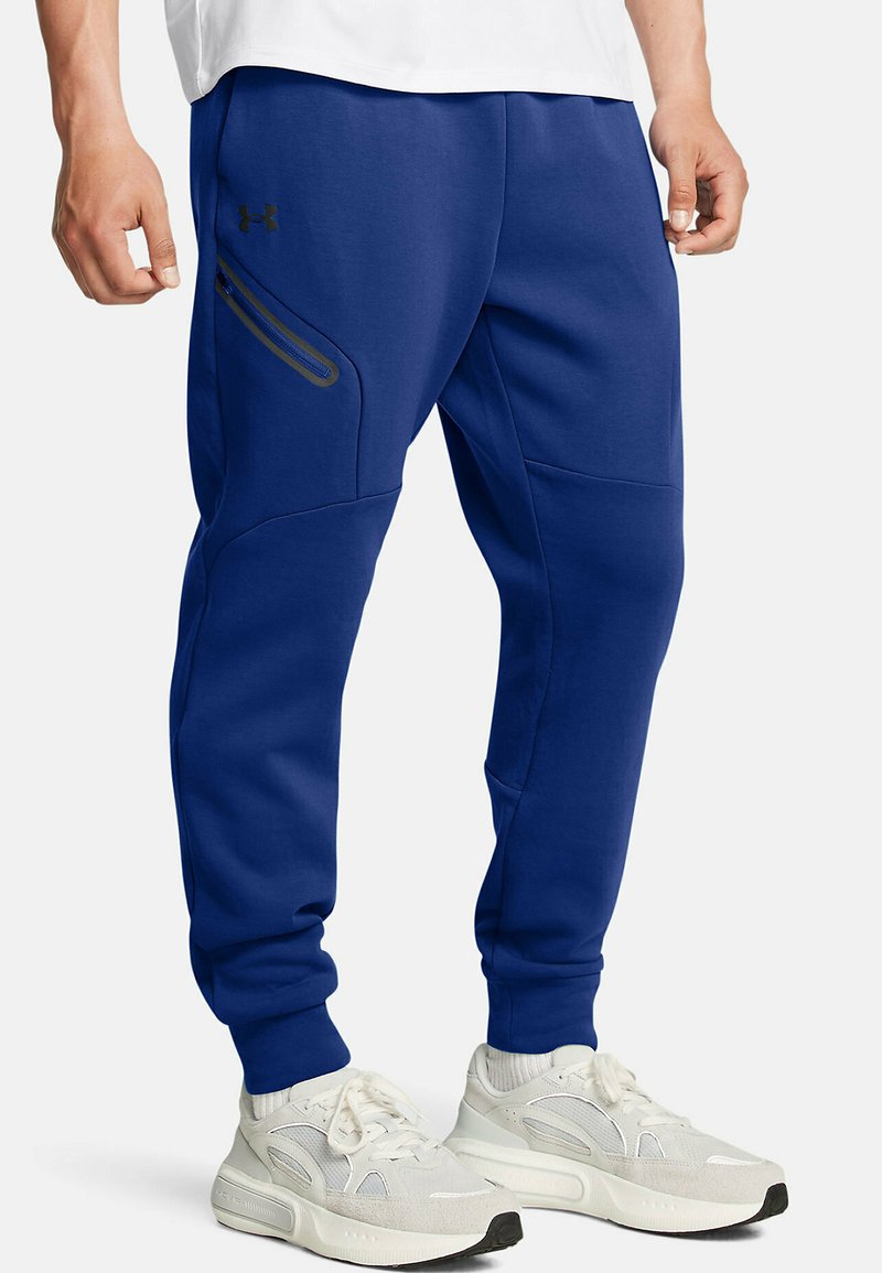 Blauwe joggingsbroek van zacht materiaal, met een ritszak aan de zijkant, taps toelopende benen en geribbelde boorden. Geaccentueerd met een zwart logo.