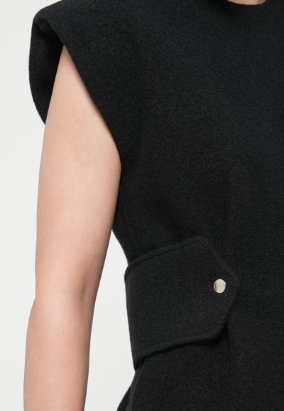 Black wool coat with structured shoulders, a side pocket featuring a silver snap button, and a soft texture.